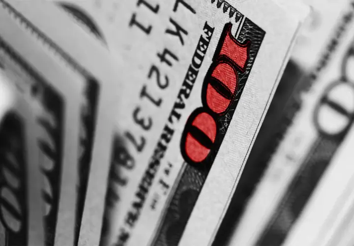 Zbliżenie na banknot 100 dolarów z czerwonym oznaczeniem liczby 100.